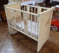 A child's wooden painted crib, one side adjustable, with a mattress covered in Disney material of