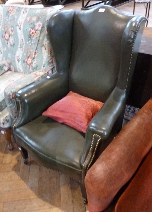 Wing armchair, in studded green leather, on square tapering legs with castors