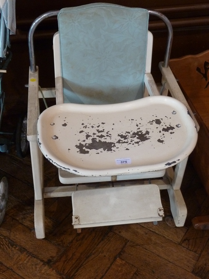 A wooden highchair with metal tray, footrest and rocking motion, on wheels