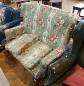 Two-seater winged sofa, with floral print upholstery, raised on cabriole legs, width 120cm