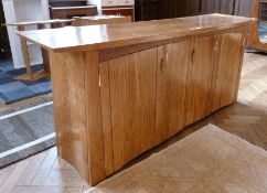 Modern oak sideboard by Nick Karey, having curved fronted top, three cupboards below, shelves