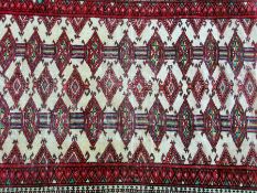 A Pakistan style wool rug, red ground with central rectangular motif with lozenge shaped