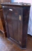 Antique oak wall hanging corner cupboard, having three three shelves enclosed by shaped framed panel