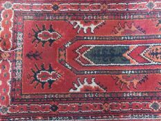 A Turkoman design narrow wool runner, dark red field, with foliate design and multiple borders