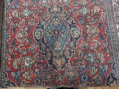 A Persian design floral wool rug, with central medallion within a red field and multiple floral