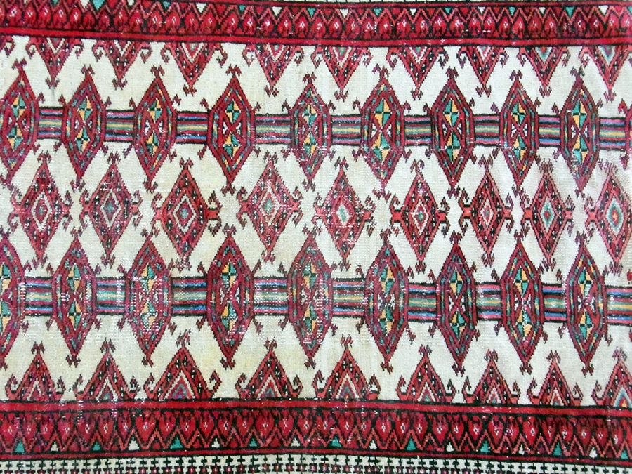 A Pakistan style wool rug, red ground with central rectangular motif with lozenge shaped