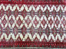 A Pakistan style wool rug, red ground with central rectangular motif with lozenge shaped