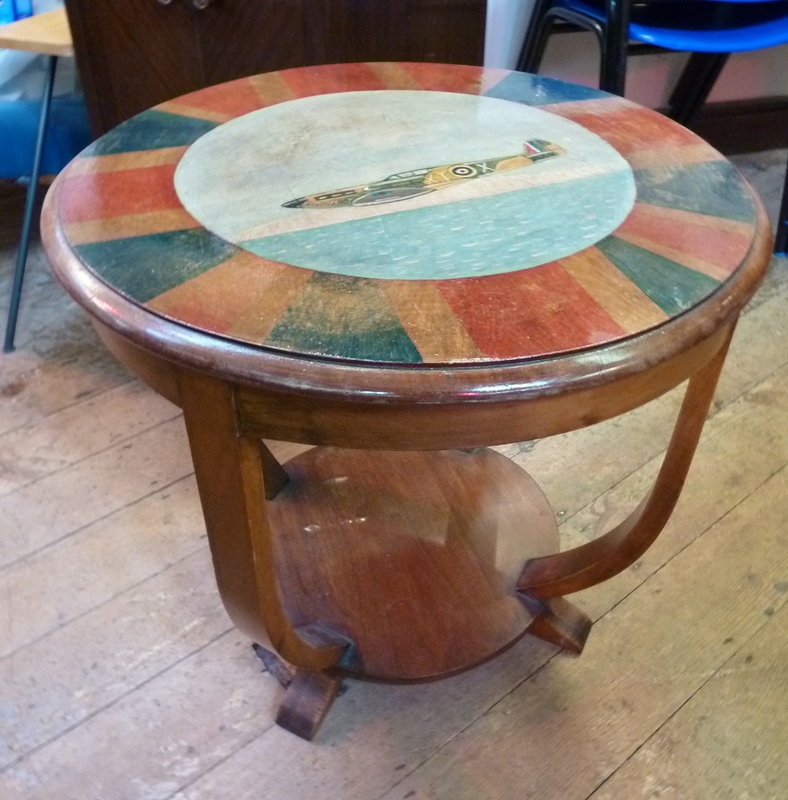 Circular stained two-tier coffee table, painted with Union Jack border and spitfire to centre,