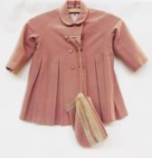 A child's pink velvet dress together with a pale pink woollen double breasted coat and matching