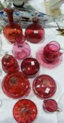 Large quantity of cranberry glass, including two water jugs, a small jug, a posy vase, lidded powder