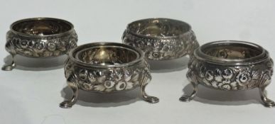 A set of four Georgian silver open salts with floral repousse decoration raised on pad feet with