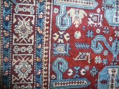 Eastern wool rug with octagonal guls and flowerheads to a red ground