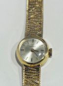 A lady's nine carat gold Omega wrist watch with circular brush metal dial, baton numerals, side