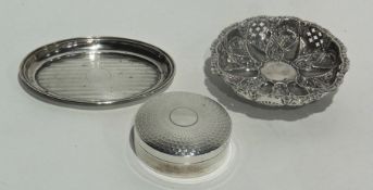 A silver circular box with engine turned cover, a bonbon dish with foliate decoration on ball feet