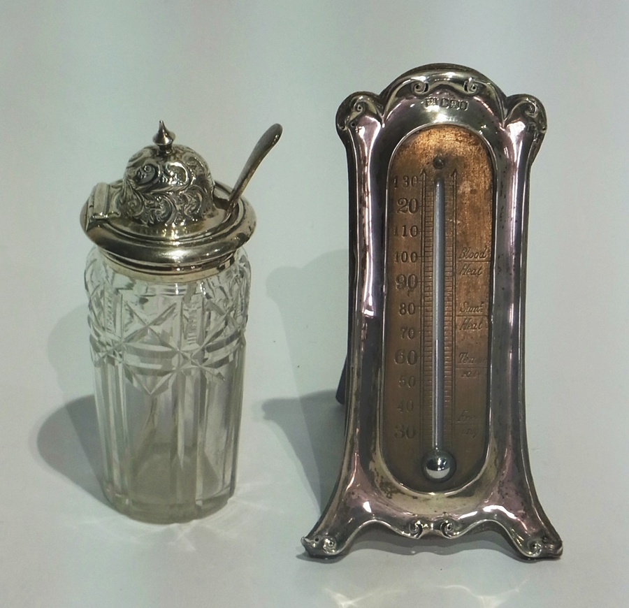 A silver cased table thermometer, Art Nouveau style, on trestle support together with a silver cut