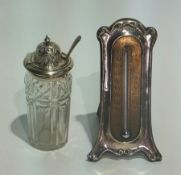 A silver cased table thermometer, Art Nouveau style, on trestle support together with a silver cut