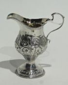 A Georgian silver cream jug, with gadrooned border, and scroll handle with floral repousse