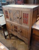 An oak Arts and Crafts Gothic revival cupboard, the central cupboard flanked by tracery panels, with