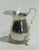 George V silver cream jug of plain form, with scroll handle, raised on pad feet, Birmingham 1913,