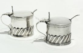 A pair of Victorian silver mustard pots with hinged tops and glass liners, and spoons, London