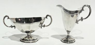 A silver twin handled oval sugar basin, of faceted form, raised on a pedestal with spreading foot