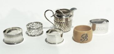 A small silver cream jug together with four silver napkin rings, various and an ivory napkin ring (