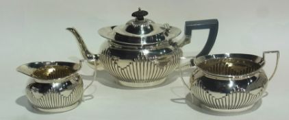 A three piece silver tea service with half fluted design comprising teapot, sugar basin and milk