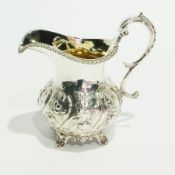 A William IV silver cream jug, with reeded border, foliate scroll handle and foliate repousse