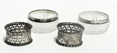 A pair of cut glass and silver-rimmed open salts, together with a pair of silver napkin rings with