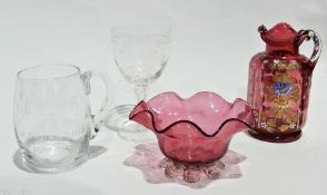 Various cranberry glass items, including a frilled vase on shell feet, two jugs, an enamelled