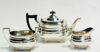 George V silver three-piece tea set of plain moulded form, raised on ball feet, comprising:- teapot,