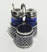 A blue glass and silver capped cruet set, within a silver stand with handle and ball feet,