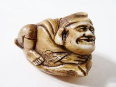 Japanese carved ivory netsuke, in the form of a man riding a fish, 5cm long, signed to base