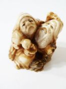 Japanese carved ivory netsuke of two seated figures and an animal, 3.5cm high