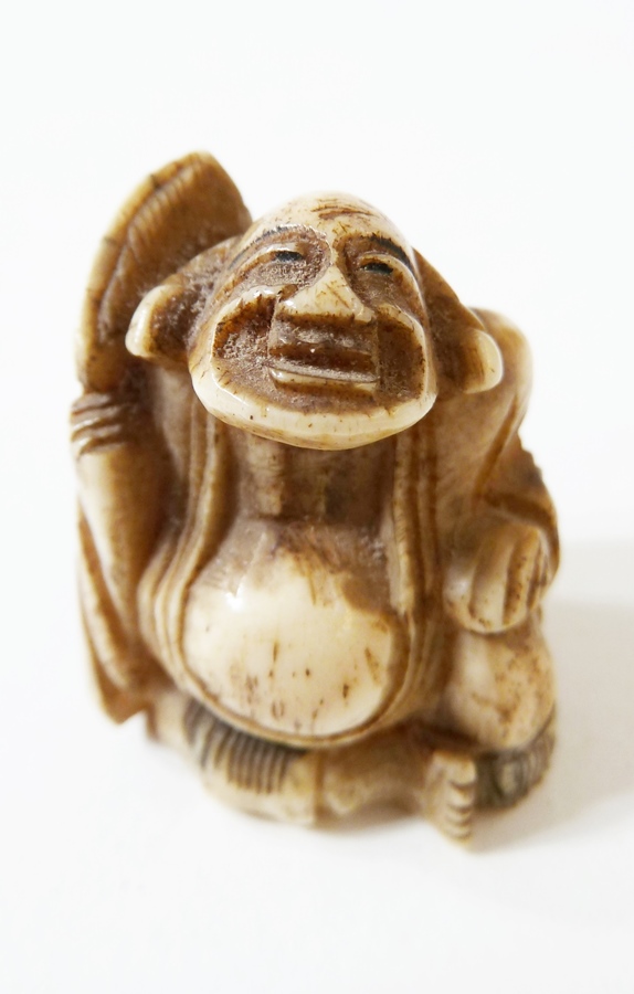 Japanese carved bone netsuke of a seated gentleman with paddle
