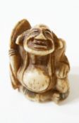 Japanese carved bone netsuke of a seated gentleman with paddle