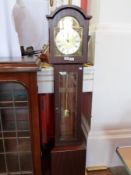 A contemporary three chime grandmother clock with silvered brass dial, glazed pendulum window on a