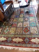 A large Persian style carpet designed with birds, flowers, trees, temples, set in squares all on a