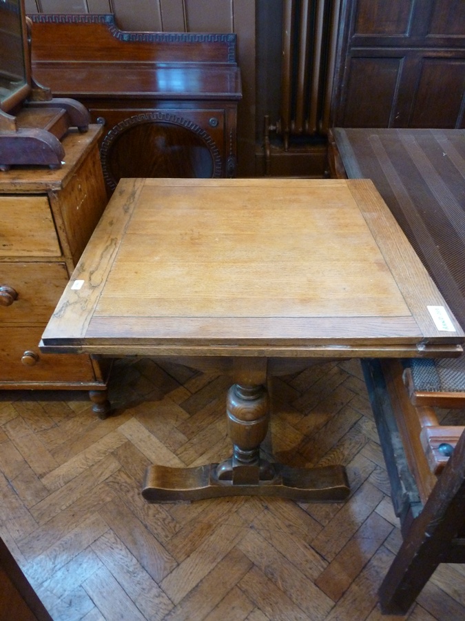 An early twentieth century oak drawer leaf dining table on turned bulbous supports, united by