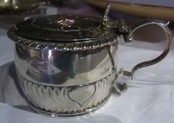 A Georgian silver circular mustard pot with foliate pattern hinged cover and scroll handle by