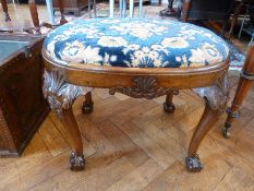 A Chippendale style carved walnut oval top stool with floral flock upholstery drop-in seat, on