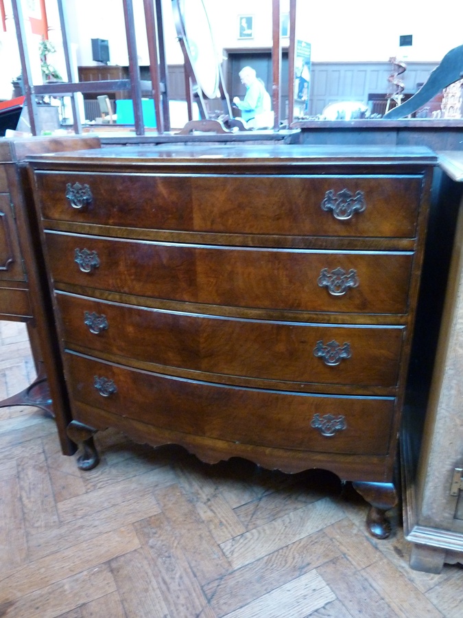 A reproduction mahogany bow front chest of four long graduated drawers raised on short cabriole legs