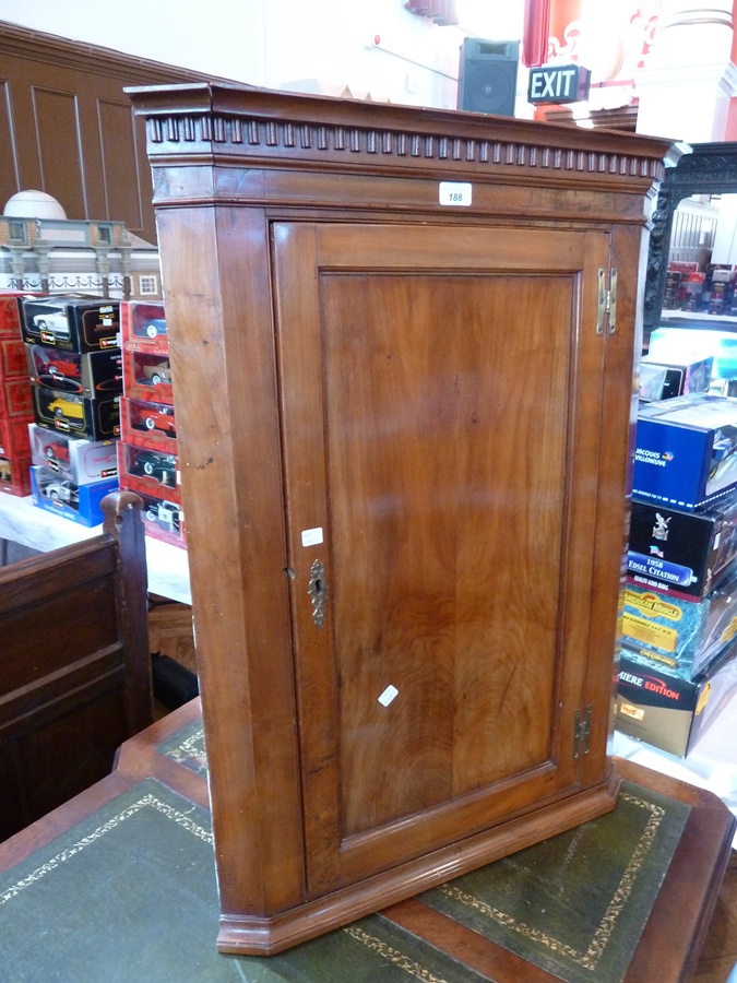 A Georgian fruitwood corner cupboard with dentil cornice, the panel door enclosing two shelves