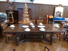 A 20th century Jacobean style carved oak dining table, with two extra leaves, on turned cup and