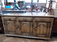 A reproduction mahogany dresser base with three frieze drawers, and three arch panel cupboards