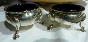 A pair of silver open salts, with gadrooned borders, blue glass liners raised on pad feet, marks
