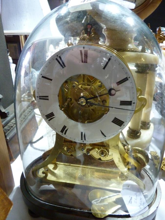 19th century brass skeleton style clock on scroll supports, mahogany plinth base under glass dome