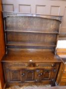 20th century oak dresser with two shelves and pegs above two drawers and cupboards below, on