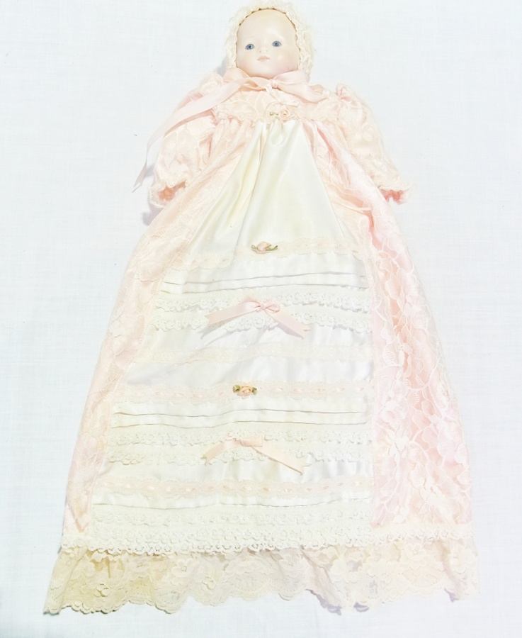 Modern bisque-headed baby doll, with fixed blue eyes, in lace-trimmed cream satin christening gown