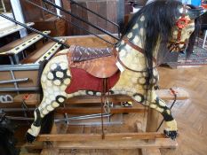 Mid-twentieth century dappled wooden rocking horse, with leather saddle, on wooden plinth